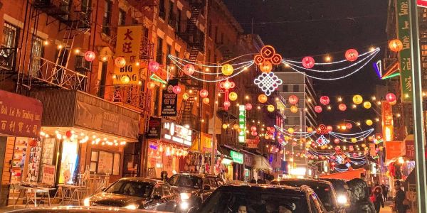 Busy Chinatown street at night with lanterns and lights.