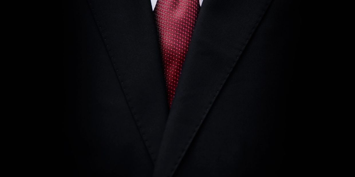 Close-up of a black suit and red tie.