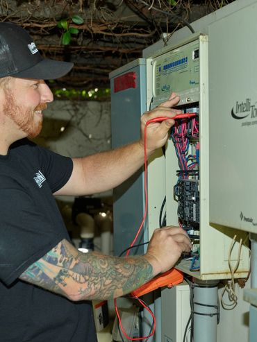 A certified pool equipment repair tech testing power inside the automation panel in El Dorado Hills