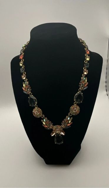 Elegant necklace with colorful gemstones on a black display stand.