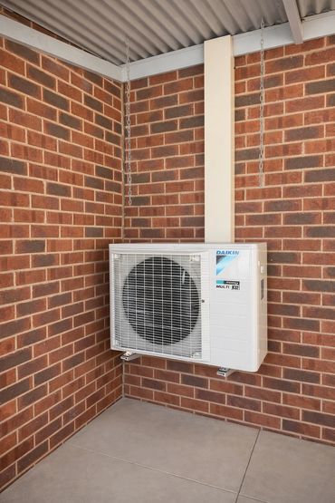 Wall-mounted Daikin air conditioning unit on brick wall.