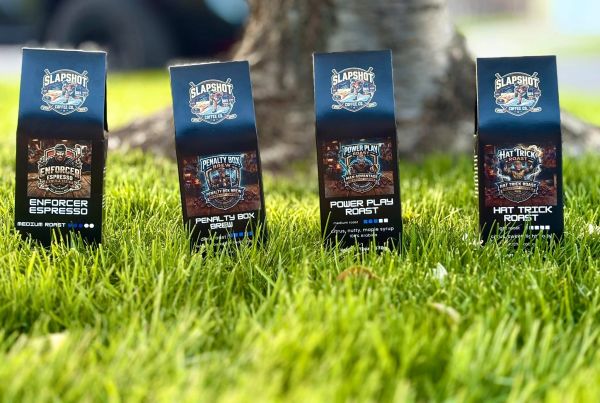 Four bags of Slapshot coffee roasts on grass.