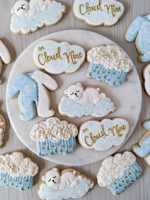Baby shower sugar cookies themed "On Cloud Nine" including pajamas, a bear, a cloud with dangles