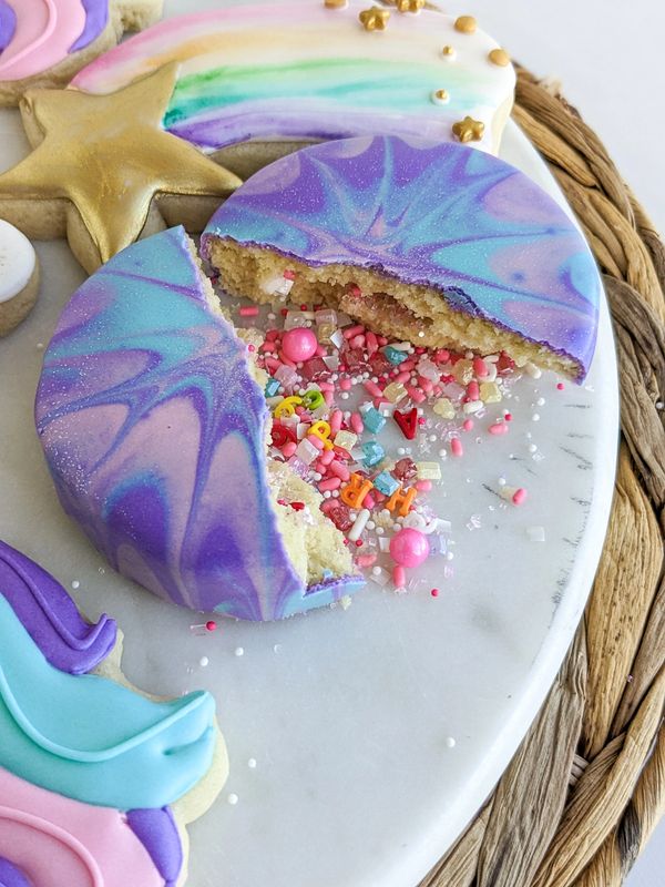 Sprinkle bomb sugar cookie cut open and spilling sprinkles onto a decorative plate