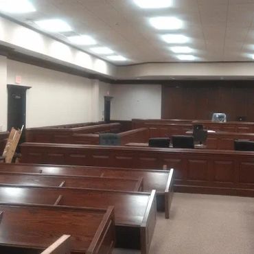 Empty courtroom with wooden benches and judge's bench.