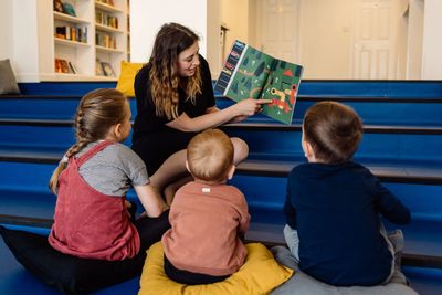 A mother reading a story book to her children inside a bookshop