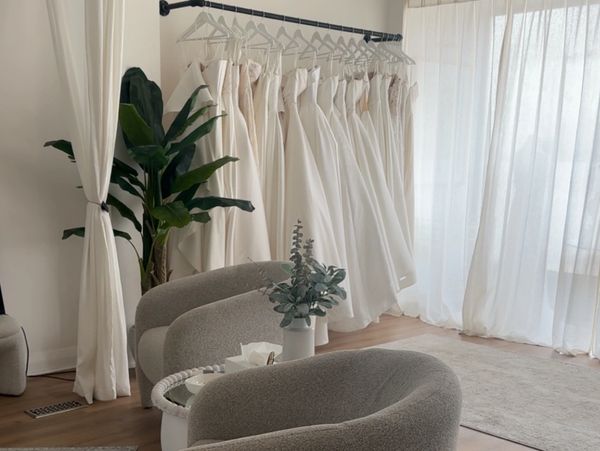 Minimalist bridal boutique with white wedding gowns and cozy seating.