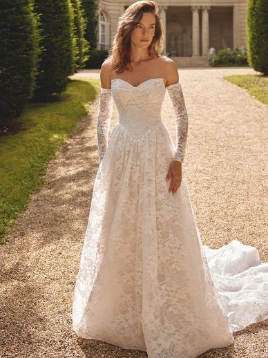 Woman in elegant white lace wedding dress with matching gloves.