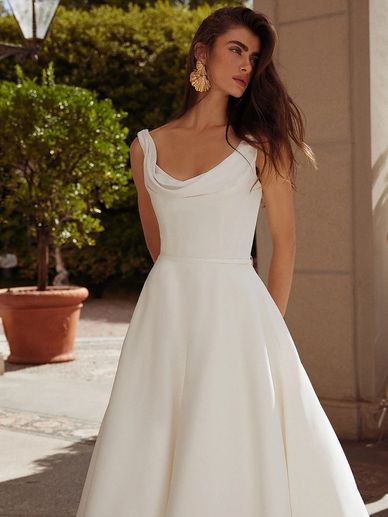 Woman in elegant white dress with statement earrings outdoors.