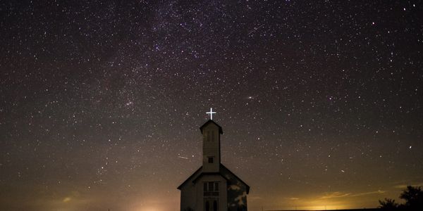 Little chapel in the woods against the background of the night starry sky in the summer