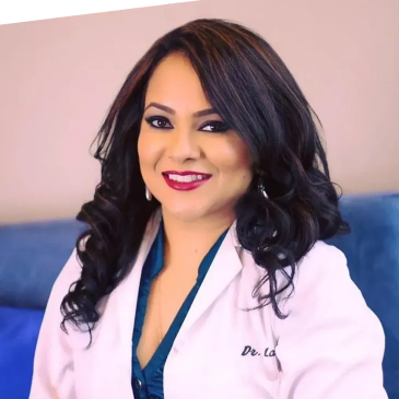 Smiling woman in a white medical coat with dark hair and makeup.
