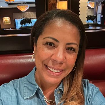 Woman smiling inside a cozy restaurant booth.