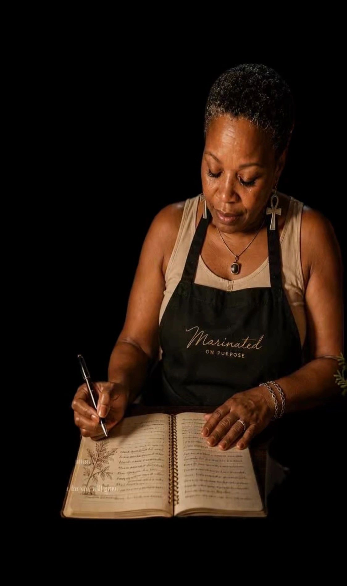 Woman writing in a journal wearing a black apron.