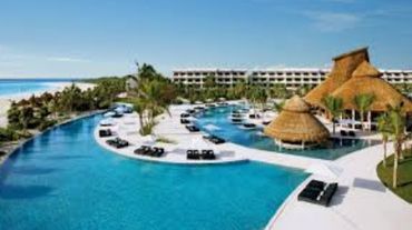 Luxurious beachside resort with a large pool and thatched-roof cabanas.