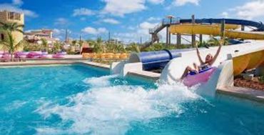 Person enjoying a water slide splash at a sunny pool.