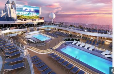 Luxurious cruise ship deck with pools and sunset ocean view.