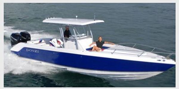 A blue and white Donzi motorboat speeding on the water with two people aboard.