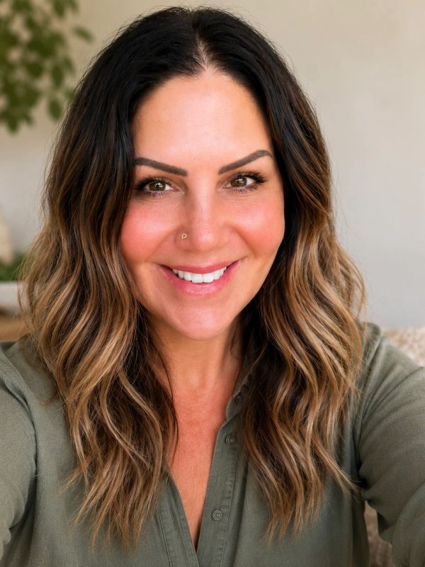 Smiling woman with wavy highlighted hair and a nose ring in a green shirt.