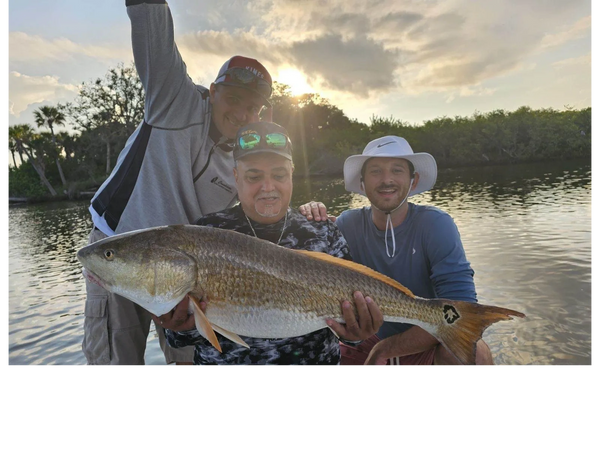 clients with a redfish they caught while on a inshore fishing trip