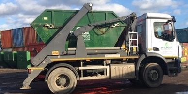 wait and load skip hire with skip loaded on a truck.