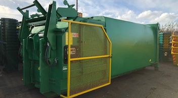 Skip Compactor.  Large green waste compactor with yellow guard.
