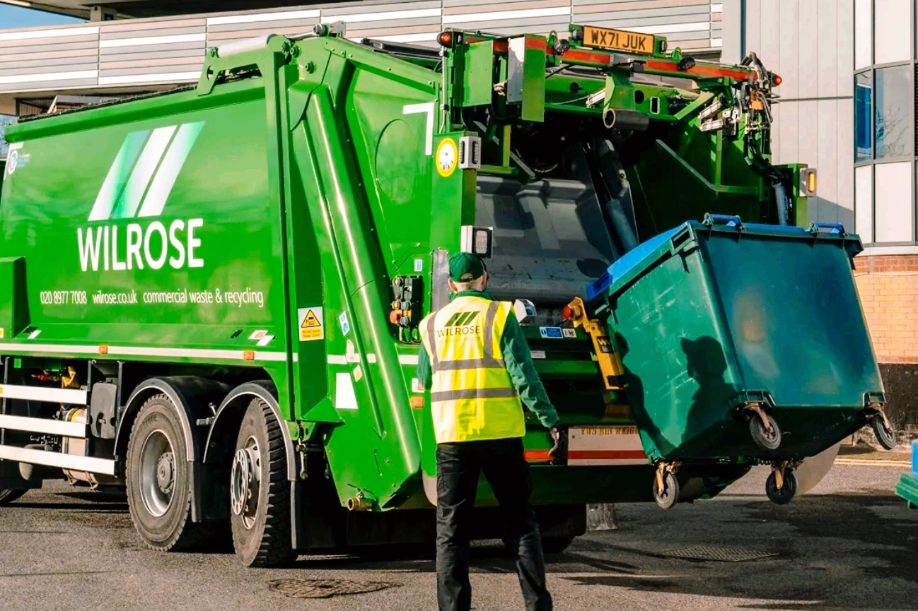 dustcart in weybridge lifting a business waste bin with wilrose driver standing next to it.