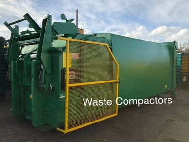 green large waste compactor supplied by wilrose with a yellow safety barrier.