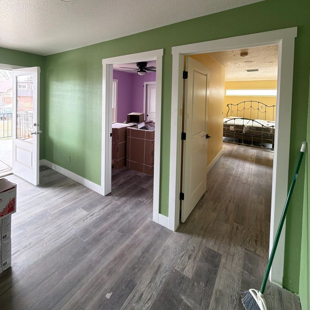 Interior of a home with green walls and open doors to colorful rooms.