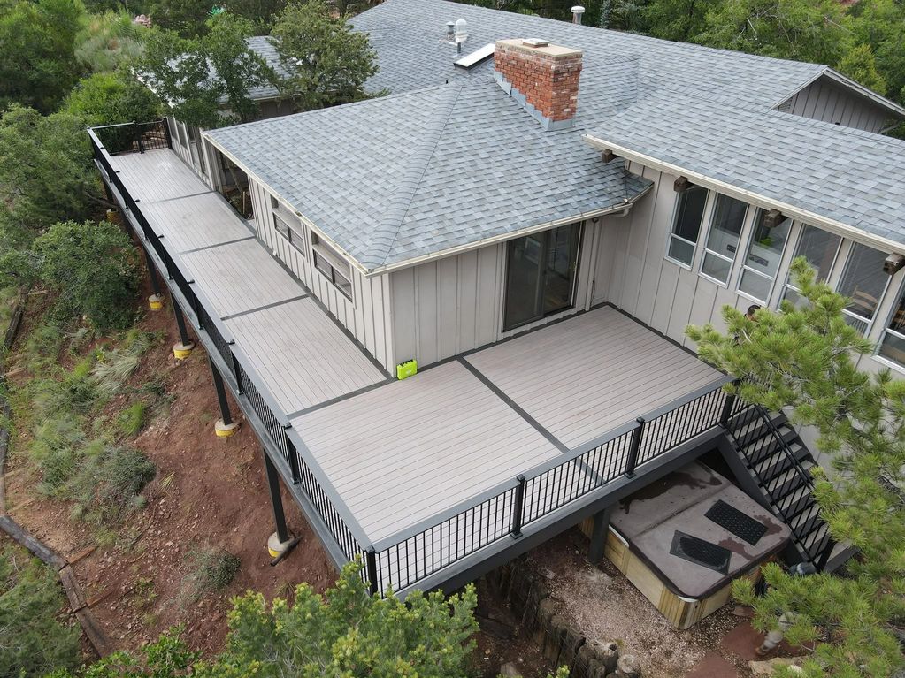 A spacious elevated deck with a black railing attached to a house with a gray roof.