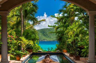 Woman enjoying a massage outdoors by a pool with a tropical view.