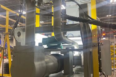 Industrial machinery with pipes and a motor inside a factory setting.