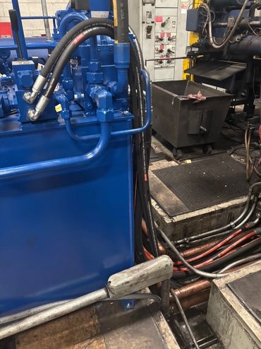 Industrial machinery with blue hydraulic components and metal pipes.