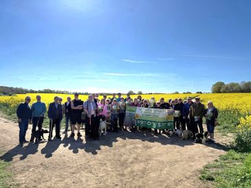 Group of people outdoors holding a banner in a sunny field.