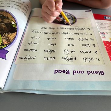 A child working on a word-matching exercise in a workbook with a pencil.