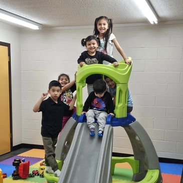 Children playing happily on an indoor slide structure.