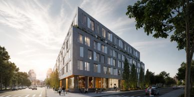 Modern angular building with large windows and greenery on a city street.