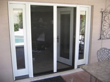 White-framed sliding glass door with a screen door leading to a patio area.