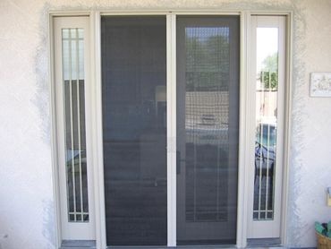 A sliding glass door with a black mesh screen and narrow glass panels on each side.