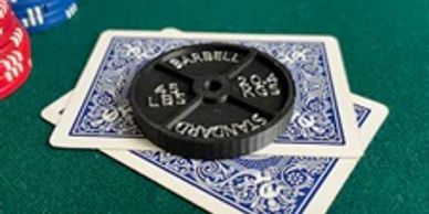 Weight plate on playing cards on a green surface.