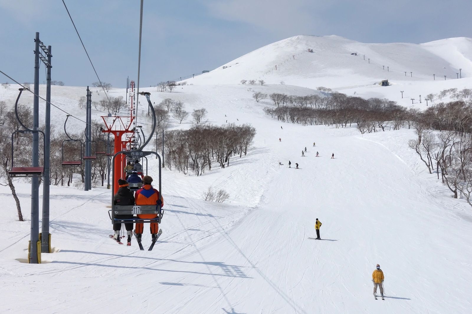 two skiers sitting on ski lift over snowy mountain niseko annupuri japan grey sky ski resort hotel