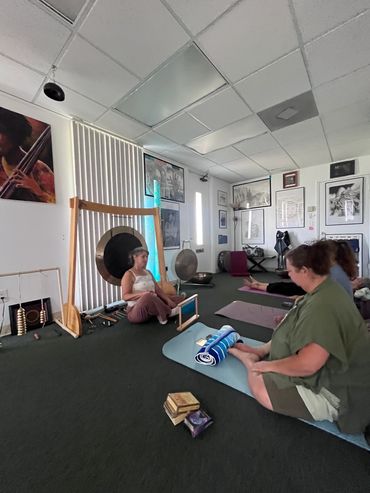 Two women in a yoga studio with gongs and musical instruments.