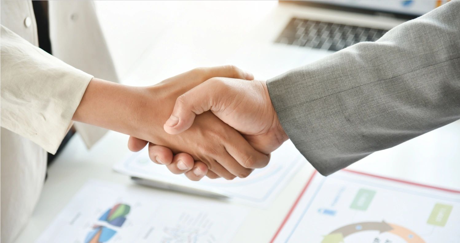 Two individuals shaking hands in a business setting.