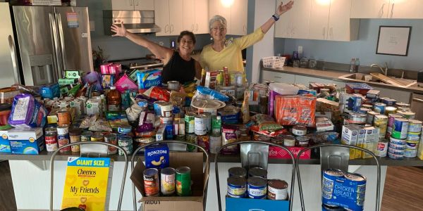 Two women celebrating food donations in a kitchen.