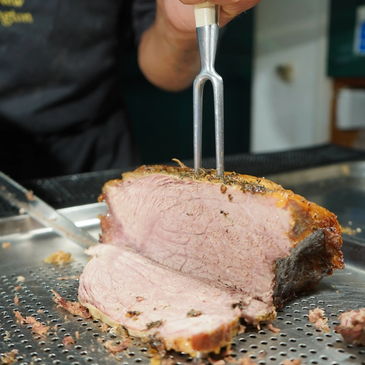 Person slicing a large piece of cooked meat.
