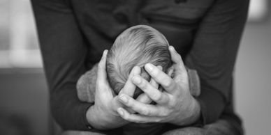 A person gently cradles a newborn baby's head in their hands.