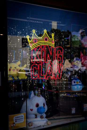 King Claw rental company neon sign and stuffed animals peering out