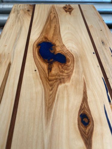 Custom charcuterie board/serving platter with blue epoxy filled voids and pronounced grain contrast.