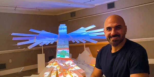 Man smiling next to a large, illuminated eagle sculpture indoors.