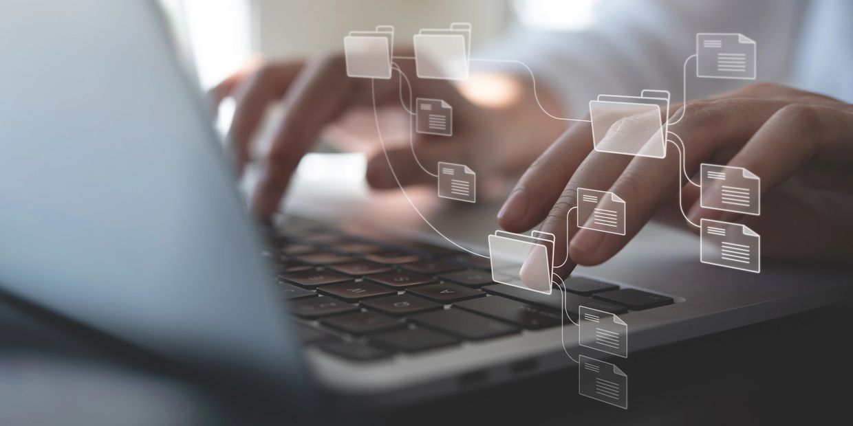 Hands typing on laptop with digital file folders and documents overlay.