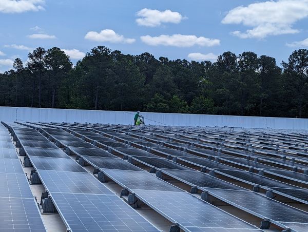 Two workers inspecting solar panels on a rooftop under a blue sky.